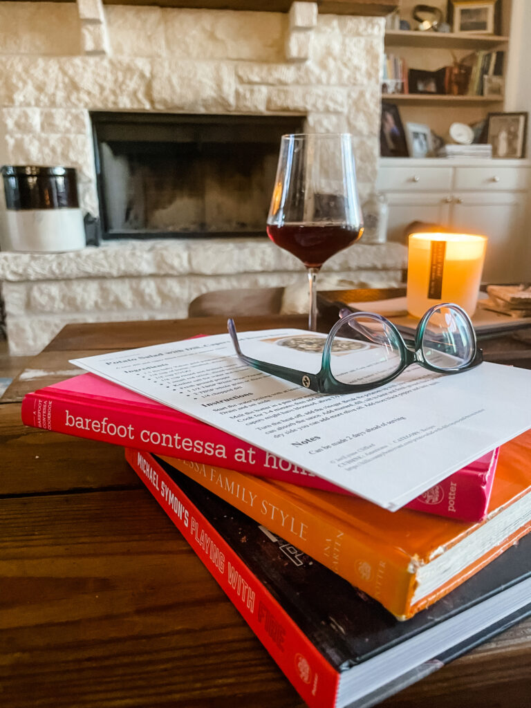 A photo of several cookbooks and a glass wine of, planning recipes for a party